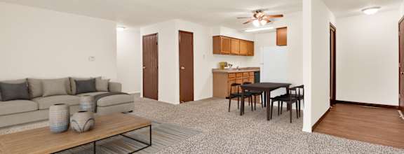 A living room with a grey carpet and a wooden coffee table. at Kimberly Club Apartments, Davenport , Iowa