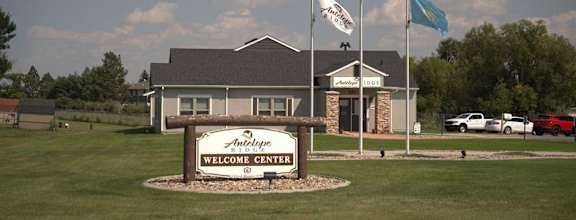 a building with flags and a welcome sign in front of it  at Antelope Ridge, Box Elder, SD, 57719