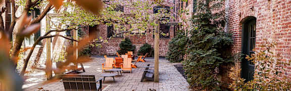 A brick pathway leads to a bench in a courtyard.