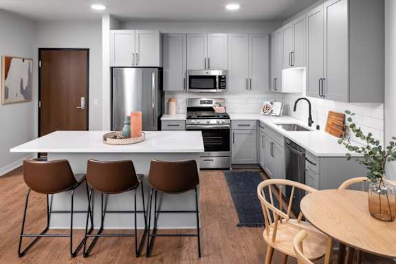 A modern kitchen with a white table and brown chairs.