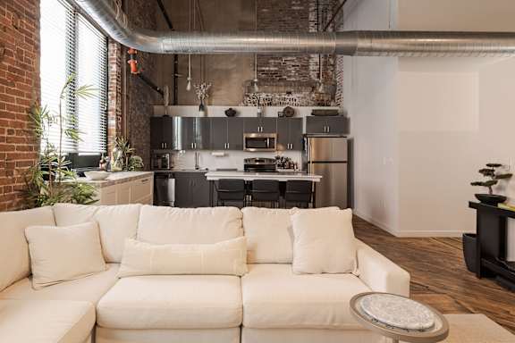 A white couch with a round tray on it in front of a kitchen.