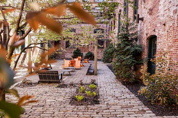 A brick pathway leads to a bench in a courtyard.