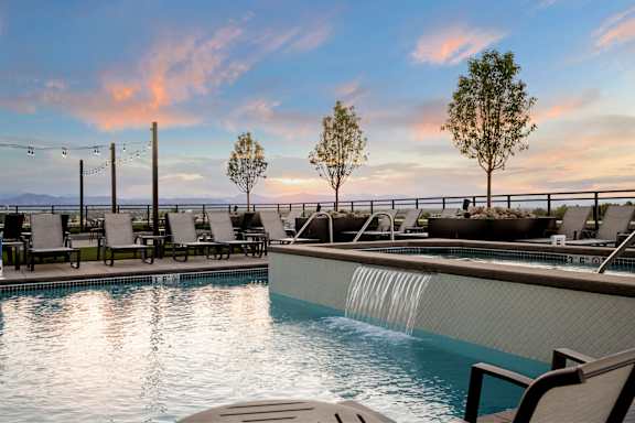 A pool with a waterfall and lounge chairs.
