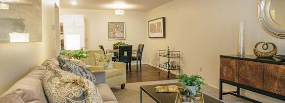 A living room with a brown couch and a glass coffee table.