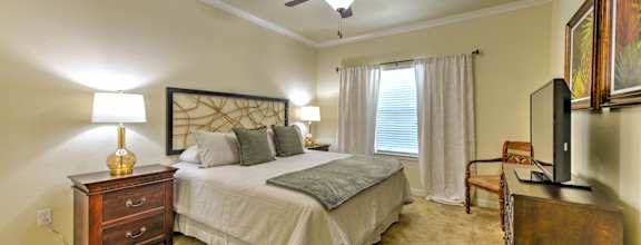 the master bedroom features a king sized bed and a flat screen tv at Hacienda Club Apartments in Jacksonville, FL