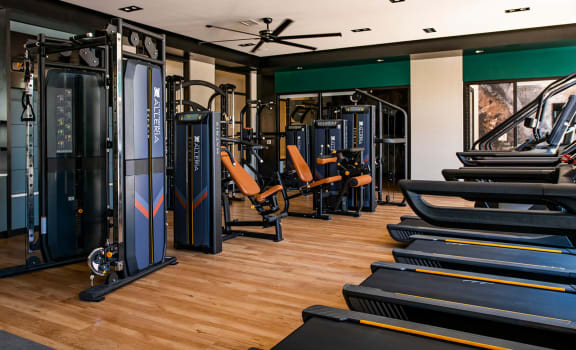 a gym with treadmills and weights on a wood floor at The Residences at Galleria, Overland Park, KS, 66211