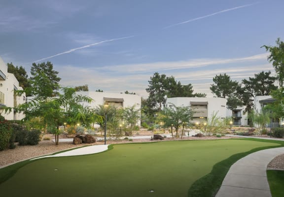 a putting green in front of a building with trees