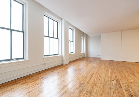 an empty living room with hardwood floors and large windows at 26 West, Managed by Buckingham Urban Living, 26 West Washington Street, IN