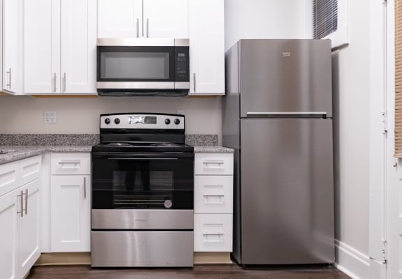a kitchen with stainless steel appliances and white cabinets at Lockerbie Court on Mass Ave Apartments, Indianapolis, Indiana