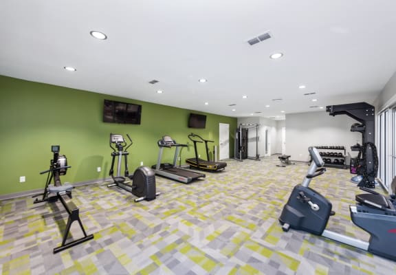 a gym with weights and cardio equipment in a building with green walls