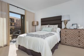 Spacious Bedroom with Bed, Dresser, Lamps, Carpet, and Sliding Glass Door with Access to Private Balcony at Nineteen800, Cupertino, California