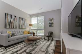 A living room with a large window, hardwood-style flooring in a luxury apartment. at Keva Flats, Exton, PA, 19341
