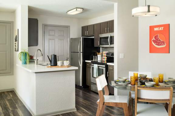 A modern kitchen with a white island and a dining table set for two.