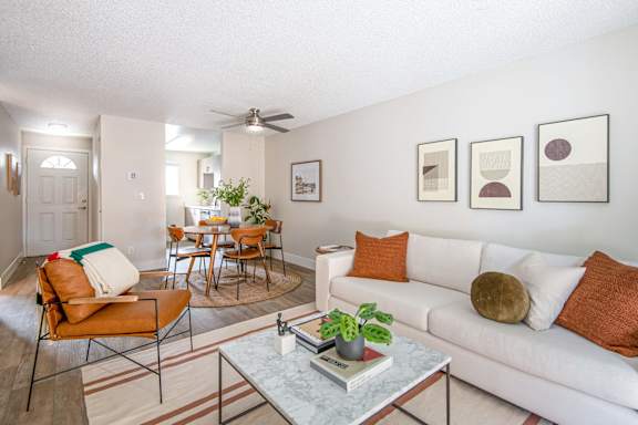 A living room with a white couch, a coffee table, and a dining table with chairs.