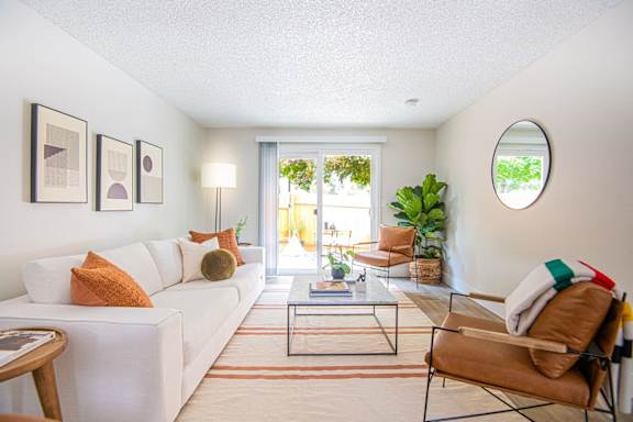 A living room with a white couch, a coffee table, and a chair.