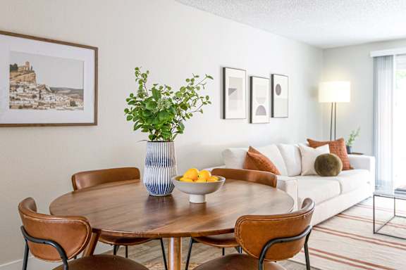 A dining table with chairs and a bowl of fruit on it.