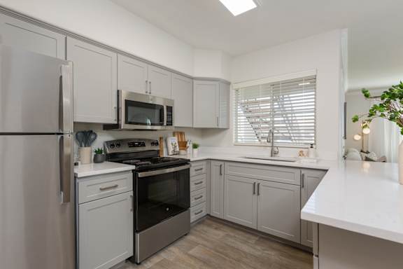 A kitchen with a refrigerator, oven, microwave, and sink.