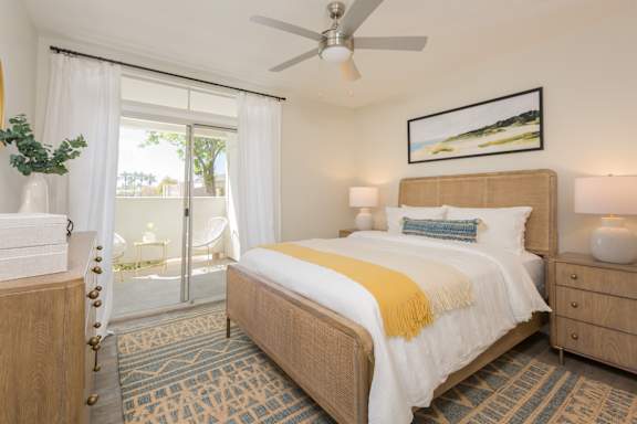 A bedroom with a bed, dresser, and ceiling fan.