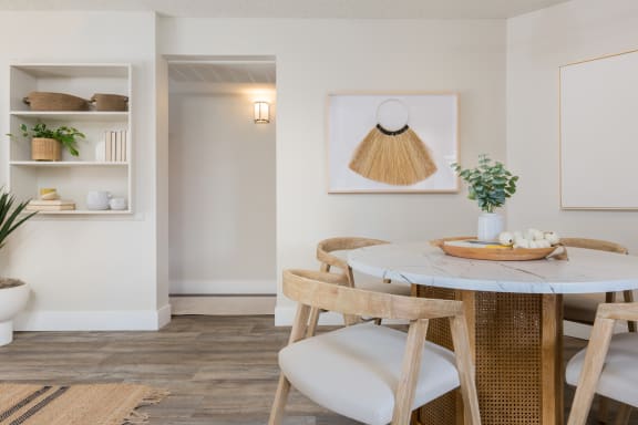 a small dining area with a round table and wooden chairs