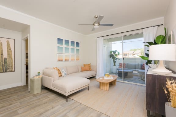 a living room with a white couch and coffee table and a sliding glass door leading to a