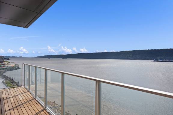 A balcony overlooks a body of water with a boat in the distance.
