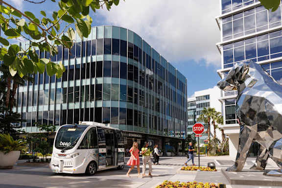 A white bus with the word "bespo" on it is parked in front of a large glass building.