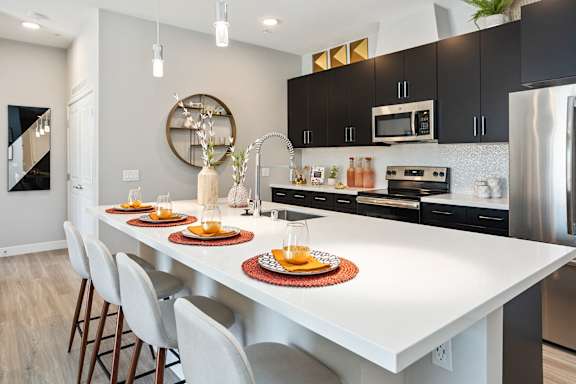 a kitchen with a large white island with four plates on it at The Hendry, Henderson, NV, 89074