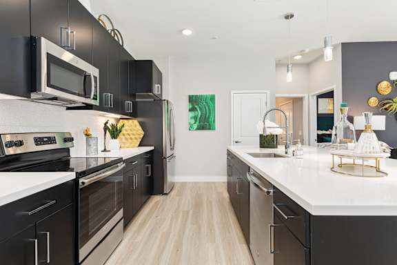 an open kitchen with stainless steel appliances and white countertops at The Hendry, Henderson, 89074