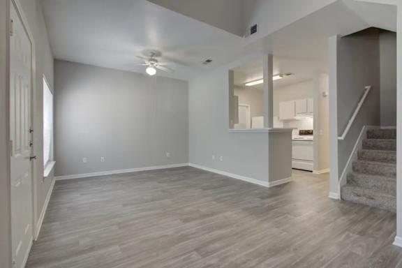 A spacious room with wooden flooring and a staircase leading to another room.