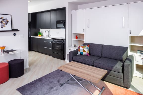 a living area with a couch coffee table and a kitchen in the background