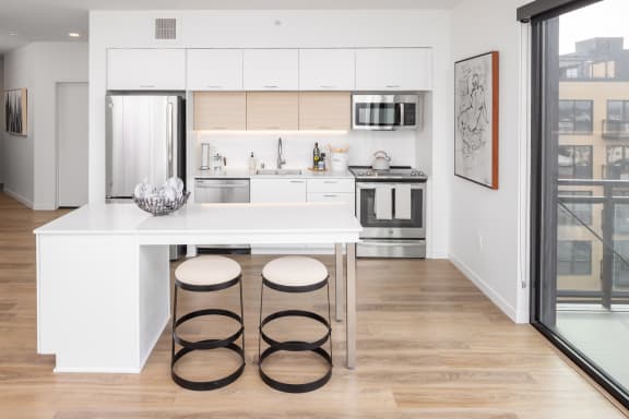 a kitchen with white cabinets and a white island with three stools