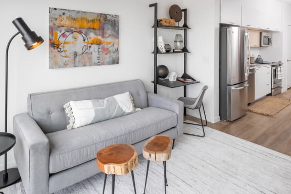 a living area with a couch coffee table and a kitchen in the background