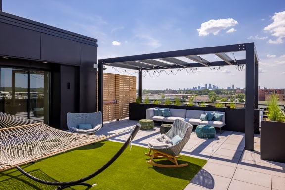 a terrace with lounge chairs and a hammock with a view of the city