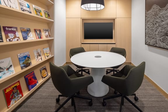 a small meeting room with a white table and four gray chairs