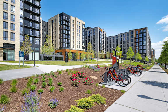 A row of modern apartment buildings with a row of bicycles parked in front.