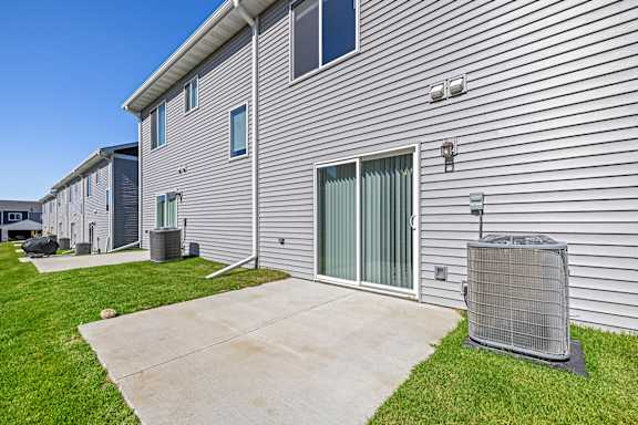 A building with a grey siding and a grey air conditioning unit in front.