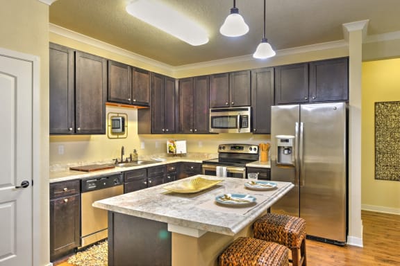 a kitchen with a large center island with a marble countertop at Hacienda Club Apartments in Jacksonville, FL