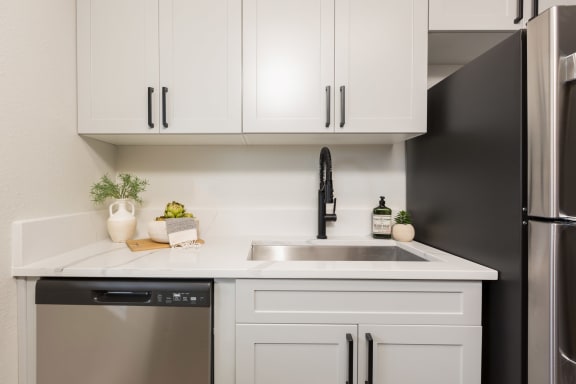 a kitchen with white cabinets and a stainless steel sink