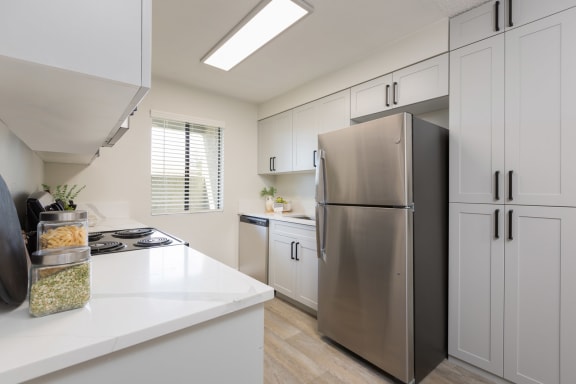 a kitchen with white cabinets and a stainless steel refrigerator