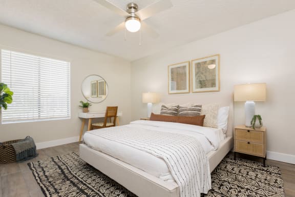a bedroom with a ceiling fan and a window with blinds
