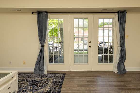 A room with a rug and a table with a white door and a window. at The Brittany Apartments, Pikesville, Maryland
