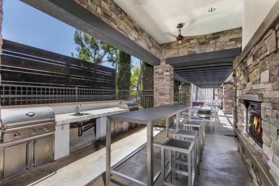 Outdoor grill and seating near fireplace at The Grove Apartments, Ontario, 91761