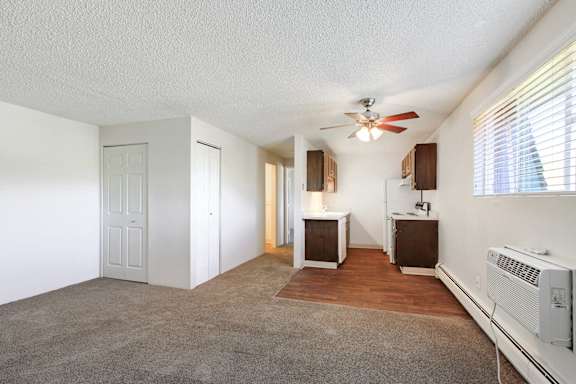 an empty living room with a ceiling fan and a kitchen at Golden Arms Apartments, Golden, CO 80401