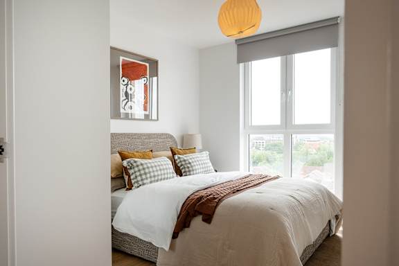 A bedroom with a bed, pillows, and a window.