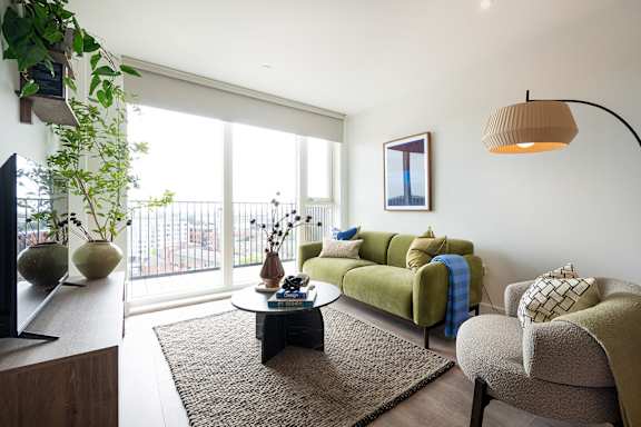 A living room with a green couch and a brown rug.