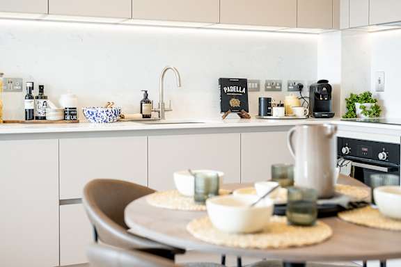 A modern kitchen with a table set for two.