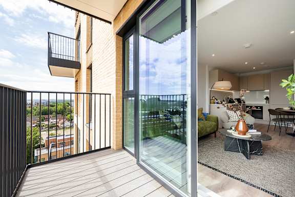 A modern balcony with glass doors overlooks a cityscape.