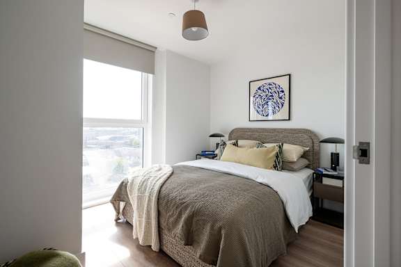 A bedroom with a bed, nightstand, and window.