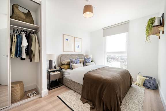 A bedroom with a bed, a wardrobe, and a window.