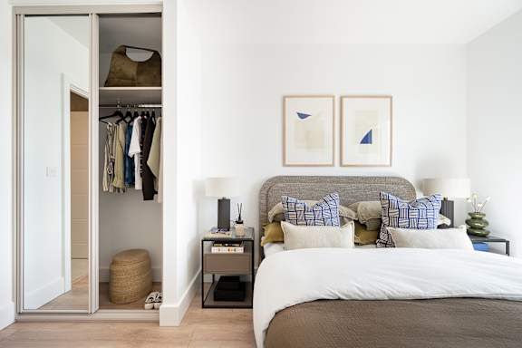 A bedroom with a large bed and two framed pictures on the wall.